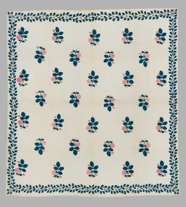 White quilt with blue leaf sprigs and a vine border